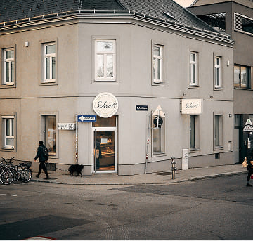 Außenansicht der Bäckerei Schrott mit Eingangstür, Filialbeschilderung und Blick ins Sortiment.