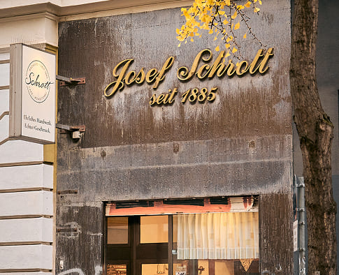 Eingang der Filiale von Bäckerei Schrott mit Schriftzug „Josef Schrott seit 1885“ über der Tür.
