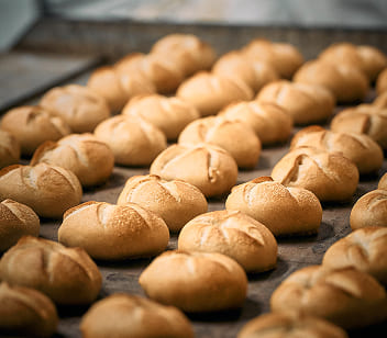 Frisch gebackene Weckerl von Bäckerei Schrott liegen in Reihen auf einem Backblech mit goldbrauner Kruste.